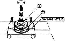 Использование приспособления DW 09921—57810 для снятия ступицы синхронизатора в сборе (1) и шестерни первой передачи/зубчатого кольца синхронизатора первой передачи (2)