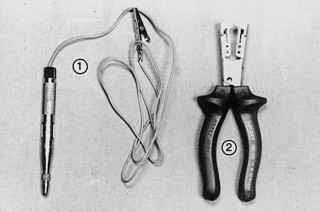 Электропробник (1) с зажимом типа «крокодил» и контактным наконечником и пассатижи (2) с изолированными ручками, с помощью которых можно снять изоляцию без повреждения провода